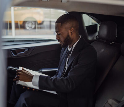 A man in a suit is sitting in the back seat of a car.